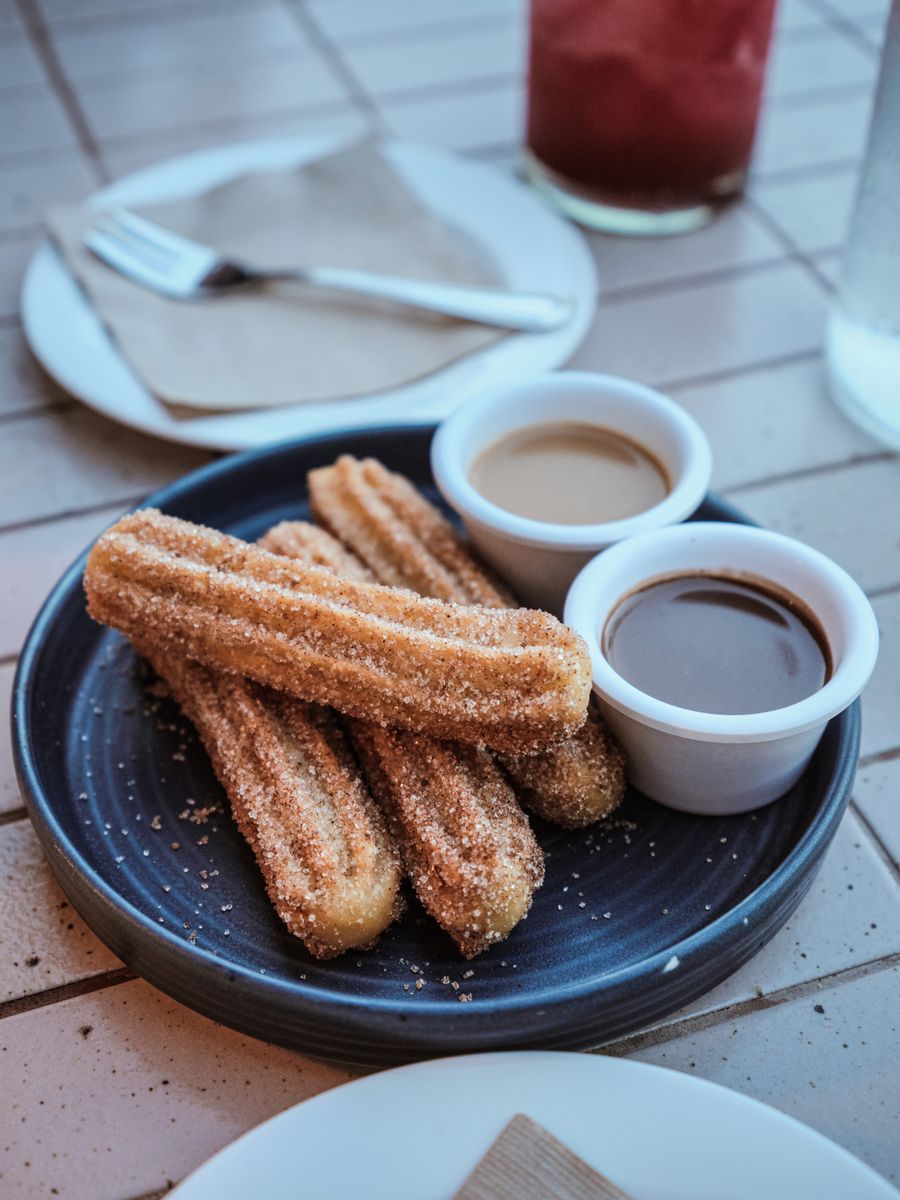 Fresh churros with dip on a ceramic plate