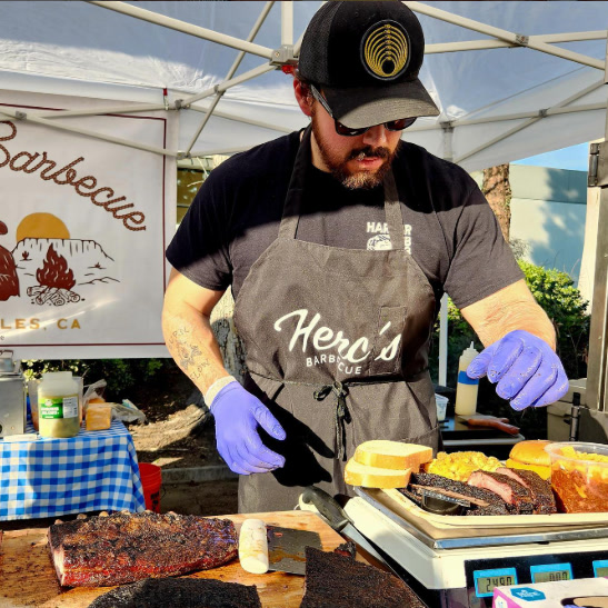 Pitmaster Adam Hernandez slicing barbecue at the Herc's Barbecue stall.