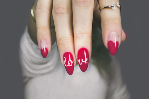 Red heart-tipped acrylic nails with lettering art