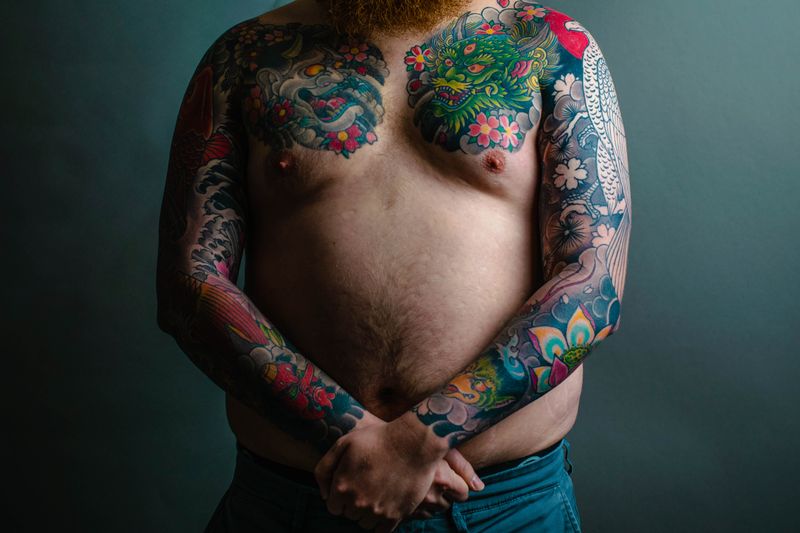 Multi-colored floral sleeve tattoo covering arm and chest
